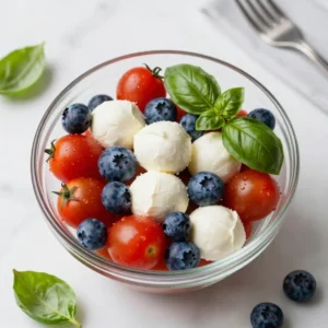 A colorful 4th of July Caprese salad featuring fresh tomatoes, mozzarella, and basil arranged in a festive pattern.