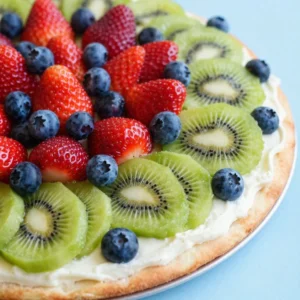 Colorful mini fruit pizzas topped with fresh strawberries, blueberries, and kiwi on a white plate