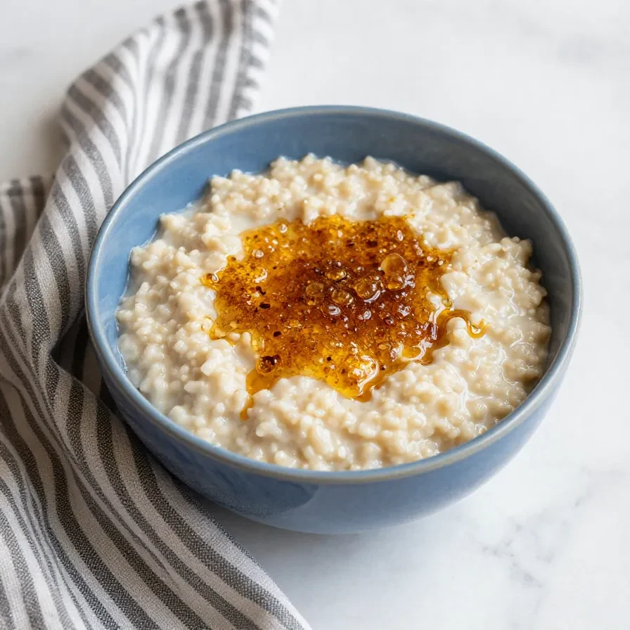 A bowl of creamy Rømmegrøt, a traditional Norwegian sour cream porridge, served with butter, sugar, and cinnamon.