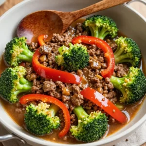 A close-up of a skillet filled with ground beef and broccoli, cooked and seasoned.