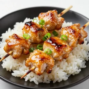 Grilled teriyaki chicken skewers served on a wooden platter with sesame seeds and green onions.