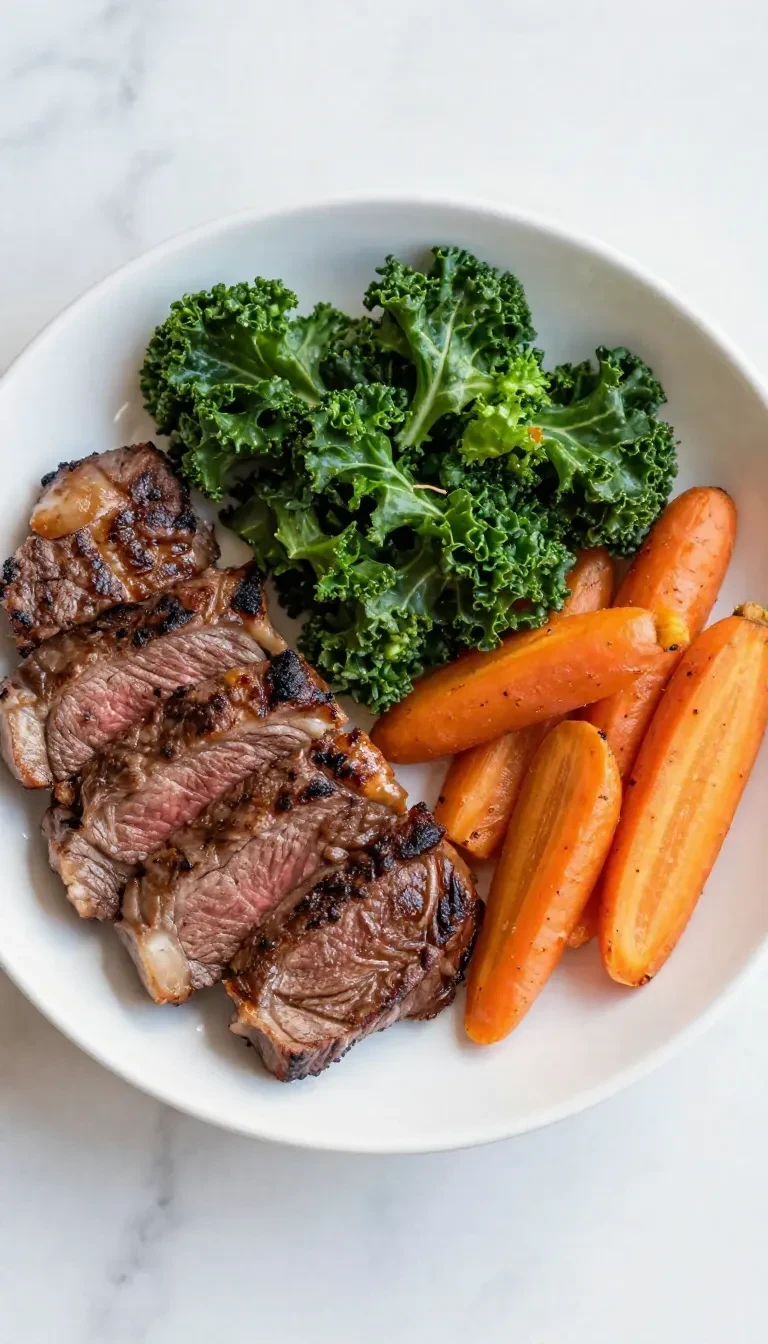 A perfectly cooked steak served with sautéed kale and roasted carrots on a plate.
